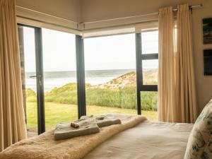 1 dormitorio con 1 cama y vistas al océano en Witsand Whalecliff accommodation en Witsand