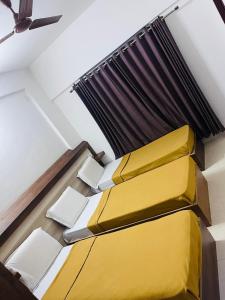 two beds in a room with yellow cushions at B Six Hotel in Bangalore