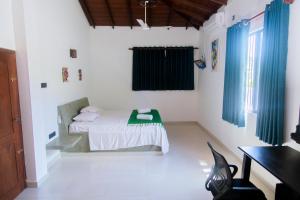 a bedroom with a bed with blue curtains and a desk at Peaceful Villa with pool near Hikkaduwa in Ambalangoda