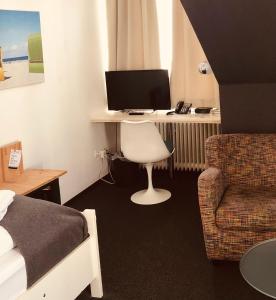 um quarto com uma secretária, um computador e uma cadeira. em beans parc hotel jade em Wilhelmshaven