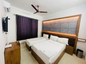 a bedroom with two beds and a ceiling fan at B Six Hotel in Bangalore