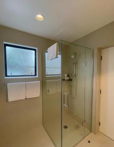 baño con ducha acristalada y ventana en Royal Park Lodge, en Auckland