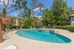 uma piscina num quintal com cadeiras e árvores em Harbour Oaks 604 em Saint Simons Island