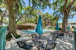 a patio with tables and umbrellas next to a pool at Turtle Cove in Saint Simons Island