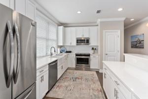 una cucina con armadi bianchi e frigorifero in acciaio inossidabile di 400 Ocean Blvd. #1200 a Golf Retreat