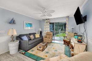 a living room with a couch and a tv at Ocean Walk H-14 in Saint Simons Island