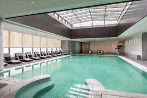 ein großer Pool in einem Gebäude mit Stühlen in der Unterkunft Marriott Executive Apartments Chongqing in Chongqing