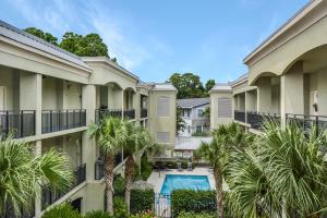 an apartment complex with a swimming pool and palm trees at Salt Therapy in Saint Simons Island