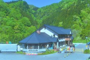 a large building with a black roof in front of a mountain at OUTDOOR STYLE AMIDA in Shōgahora