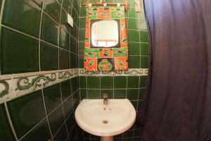 a green tiled bathroom with a toilet and a mirror at Kipepeo Lodge Zanzibar in Jambiani