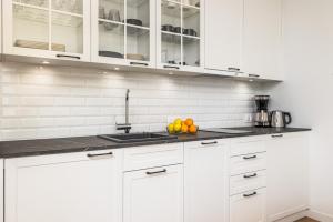 a white kitchen with white cabinets and oranges on the counter at Sunny Coast Studio in Pobierowo by Renters in Pobierowo
