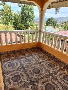 balcón con suelo de baldosa y barandilla blanca en Zack's Serene House, en Kisii