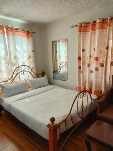a bedroom with a large bed with orange and white curtains at Zack's Serene House in Kisii