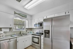 eine Küche mit weißen Schränken und einem Kühlschrank aus Edelstahl in der Unterkunft Courtyard Villa C-4 Butterfly Villa in Saint Simons Island