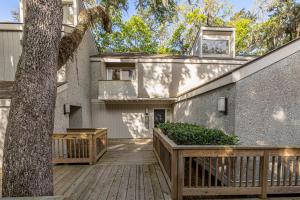 una casa con terrazza in legno accanto a un albero di Fairway Villa #410 a Saint Simons Island