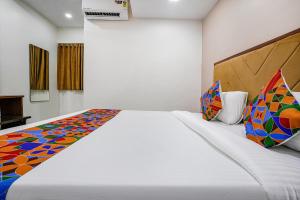 a bedroom with a large white bed with colorful pillows at FabHotel New 7 Star in Mumbai