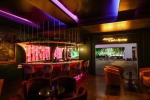 un restaurante con un bar con sillas de color naranja e iluminación púrpura en Wonderla Resort, en Kumbalgod