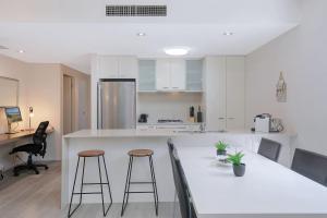 una cocina con encimera blanca y taburetes de bar en 'Attiva' A Brisbane Gem with Pool and Private Patio en Brisbane