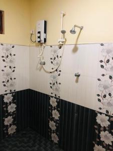 Sigiri Sunanda Home Stay في سيجيريا: حمام مع دش مع الزهور على الحائط