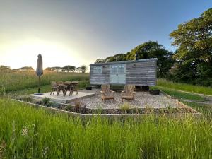 a cabin with benches and tables in a field at Private and peaceful stay in a Luxury Shepherds Hut near Truro in Truro