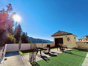eine Terrasse mit Tisch und Stühlen und ein Gebäude in der Unterkunft Boho Regency in Shimla
