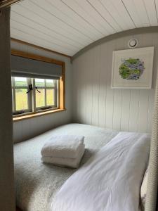 a bedroom with a white bed with a window at Private and peaceful stay in a Luxury Shepherds Hut near Truro in Truro