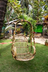 a wicker swing hanging from a tree in a yard at Rockit Cafe & Stay in Palolem