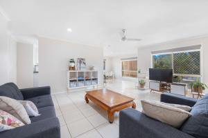 a living room with two blue couches and a coffee table at Bay Breeze - Easygoing Beachside Living for Families in Hervey Bay