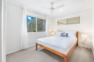 a white bedroom with a bed and a window at Bay Breeze - Easygoing Beachside Living for Families in Hervey Bay