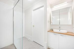 a white bathroom with a sink and a shower at Bay Breeze - Easygoing Beachside Living for Families in Hervey Bay +12 photos