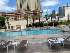 a large swimming pool with chairs and a building at Entire Strip View Suite in Las Vegas