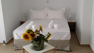 a bedroom with a bed with a vase of flowers on a table at Niovi Boutique Apartments in Afitos