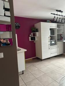 a kitchen with white cabinets and a purple wall at Appartement centre Granville in Granville