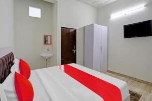 1 dormitorio con 1 cama roja y blanca y TV en OYO 81321 Flagship Golden Crest Inn, en Noida