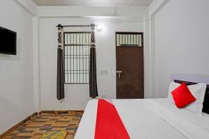 1 dormitorio con 1 cama con almohadas rojas y puerta en OYO 81321 Flagship Golden Crest Inn, en Noida