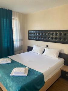 ein Schlafzimmer mit einem großen weißen Bett mit einer blauen Decke in der Unterkunft Kamelot Hotel in Pasarel