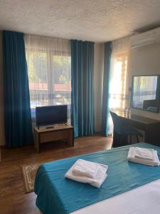 ein Hotelzimmer mit einem Bett, einem Schreibtisch und einem TV in der Unterkunft Kamelot Hotel in Pasarel