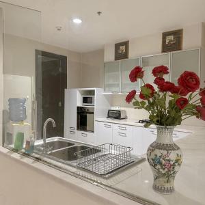 a kitchen with a vase with red roses in it at Senayan Jakarta Oasis - Gym, Pool, Netflix in Jakarta