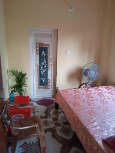 ein Schlafzimmer mit einem Bett, einem Stuhl und einem Ventilator in der Unterkunft Royal home homestay in kolkata