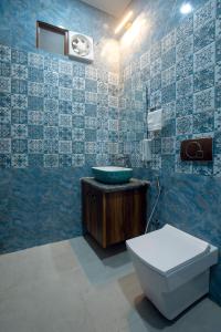 a blue tiled bathroom with a toilet and a sink at Madhav Residency in Mathura