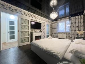 a bedroom with a white bed and a fireplace at Уютная Квартира с ванной. in Pavlodar