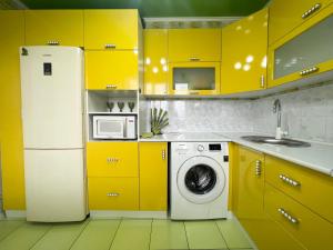 a yellow kitchen with a refrigerator and a washing machine at Уютная Квартира с ванной. in Pavlodar