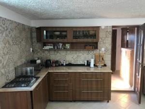 a kitchen with wooden cabinets and a counter top at Kőlépcsős Vendégház in Nyúl