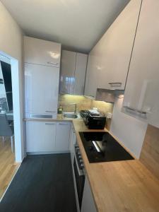una cucina con armadi bianchi e un forno a piano cottura nero di George-Beach Apartment Ossiachersee/Gerlitzen a Bodensdorf