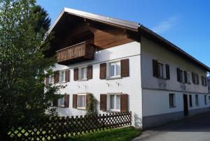 Biały dom z balkonem i ogrodzeniem w obiekcie Ferienhaus Lila w mieście Hittisau