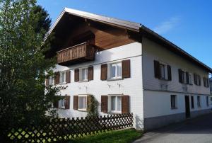 a white house with a balcony and a fence at Ferienhaus Lila in Hittisau