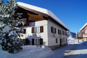 a building with snow on the side of it at Ferienhaus Lila in Hittisau