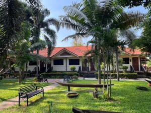 a park with benches and palm trees in front of a building at Payamai Resort in Ban Nong Nam Khan