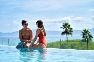 un homme et une femme assis dans une piscine dans l'établissement Iberostar Selection Albufera Playa All Inclusive, à Playa de Muro