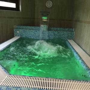 una gran piscina de agua verde con un reloj. en Meggyes Hotel, en Szerencs